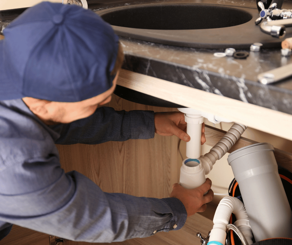 a male plumber repairing a kitchen sink at a Maple Ridge residence